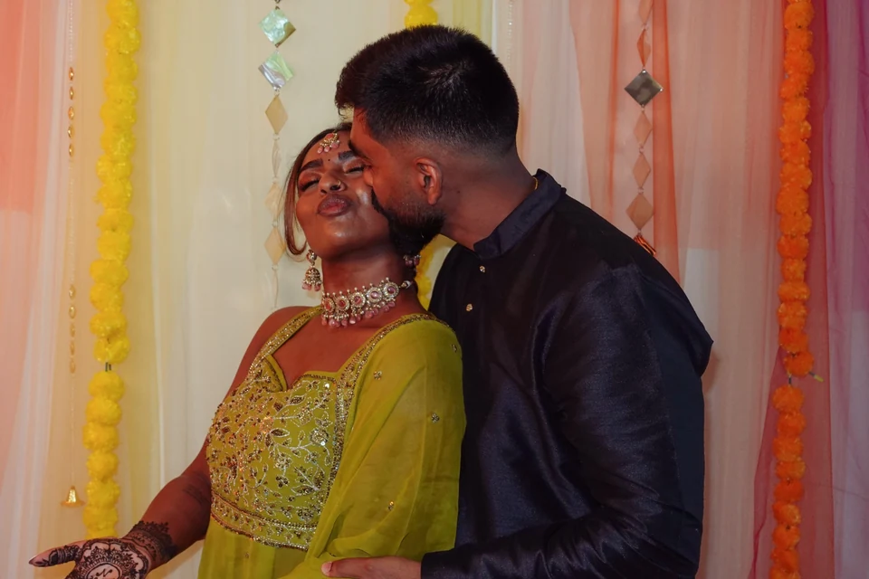 A couple sharing a kiss in front of colourful wedding decorations