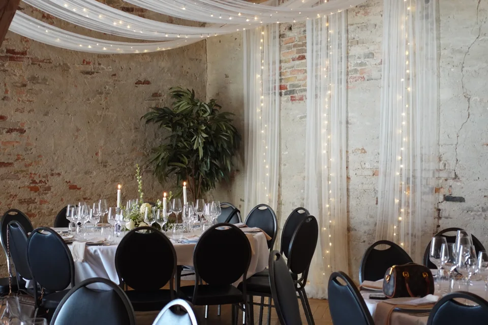 A reception room with draped fabric and candlelit tables